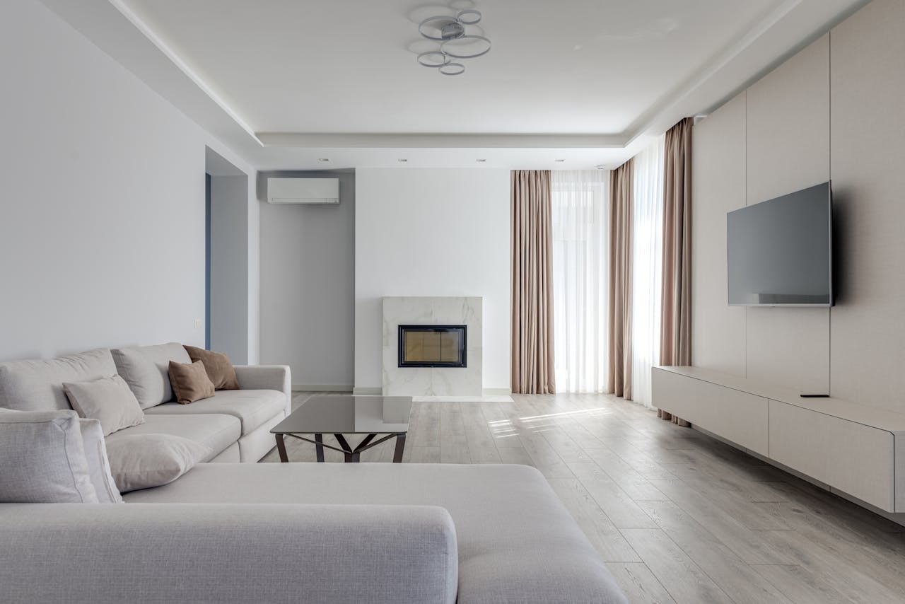 Interior of light living room in pastel colors with comfortable couch near glass table and TV set